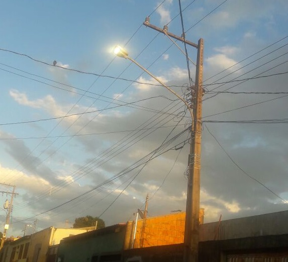 Na Rua Neide Morcazel Blota, no bairro Aero Rancho, a luz do poste fica acesa em pleno dia, disputando com a luz solar