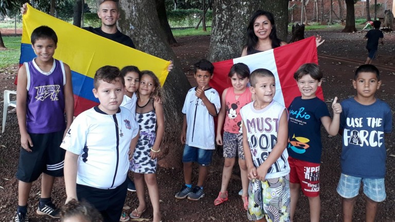 Ostentando os Pavilhões dos seus países, a peruana Maryori Aguirre e o colombiano Henry Vasquez, em intercâmbio com as crianças do CRAS Aero Rancho